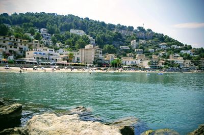 Buildings by sea against sky