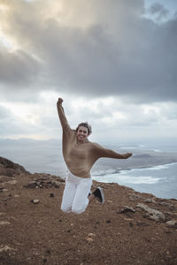 Full length of man with arms raised against sky