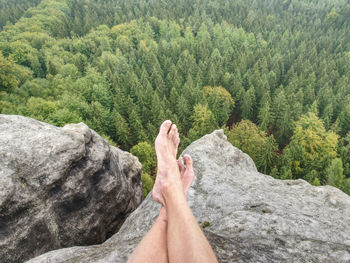 Man taking a break in nature and looking from summit down at the distant landscape.