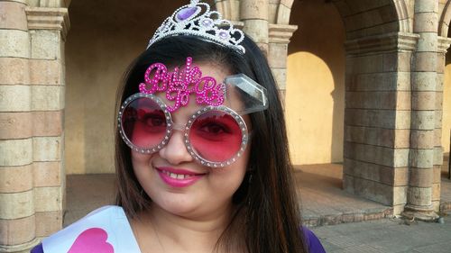 Portrait of smiling bride wearing props against building