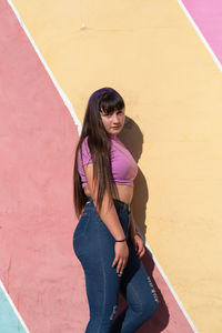 Portrait of beautiful teenage girl posing against colorful wall