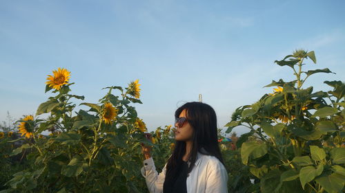 Woman standing by sunflower against sky