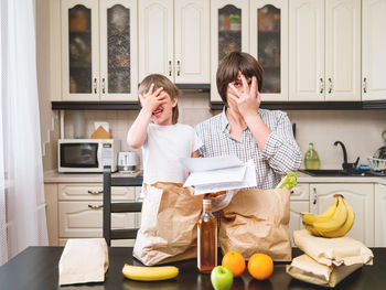 Father and son covering face with hand in kitchen