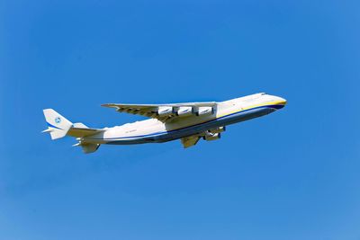 Low angle view of airplane flying against clear blue sky