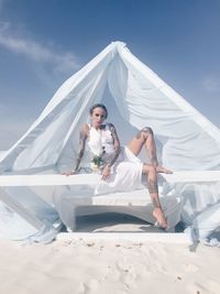 Young woman sitting on white bed