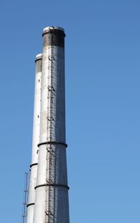 Low angle view of factory against clear blue sky