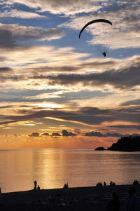 Silhouette man flying over sea against sky