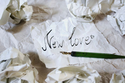 High angle view of new love text by crumpled paper on table