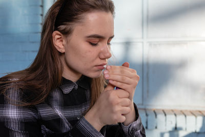 Close-up of young woman igniting cigarette