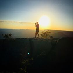 Silhouette man standing on land against sky during sunset