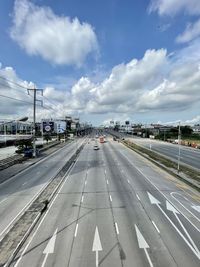 Vehicles on road against sky in city