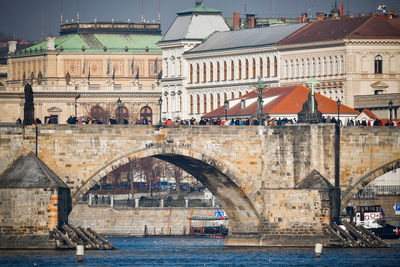 Arch bridge over river against buildings in city