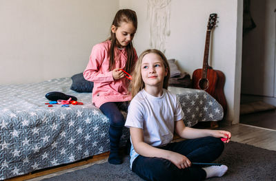 Two girls schoolgirl friends play at home, do their hairstyle