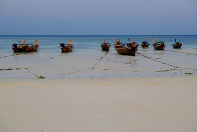 Boats moored on sea against clear sky