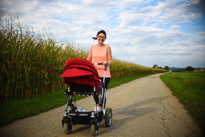 Portrait of woman with stroller standing on road 