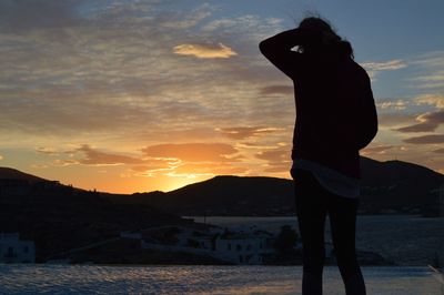 Silhouette woman standing by sea against sky during sunset