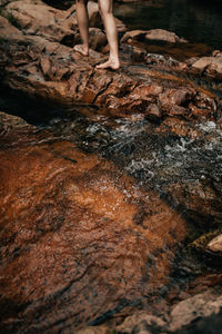 Low section of woman standing on rock in water