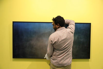 Rear view of man standing against wall