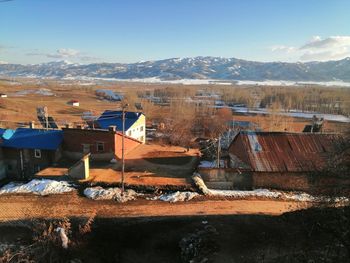 Houses by buildings against sky during winter