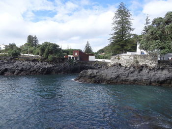 Houses by sea against sky