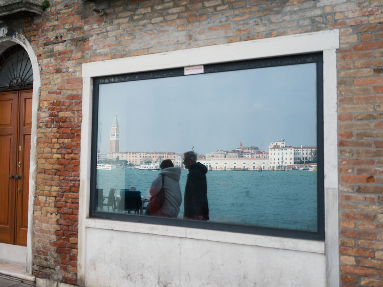 REAR VIEW OF MAN STANDING BY WINDOW IN CITY