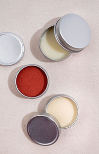 Colorful lip balms in round tin cases on leather with shadow overlay, mockup design, label