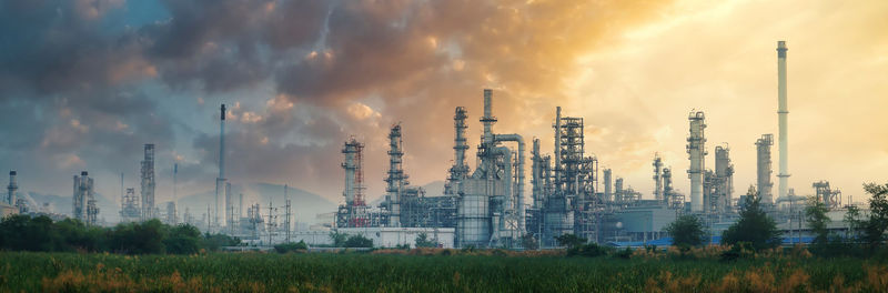 Panoramic view of factory against sky during sunset