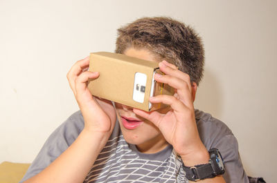 Close-up of boy watching in smart phone through cardboard virtual reality simulator