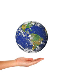 Cropped hand of person holding globe against white background