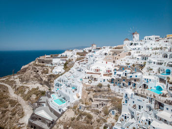 High angle view of buildings by sea against blue sky