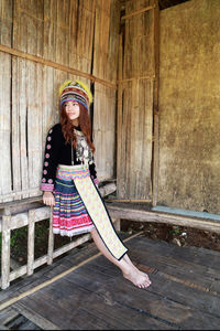 Full length of woman sitting on wood