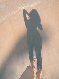 Shadow of man walking on sand at beach