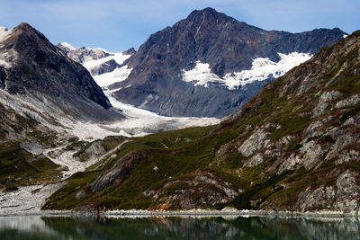 Scenic view of lake by snowcapped mountains against sky