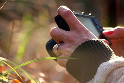 Close-up of hand holding cigarette against blurred background