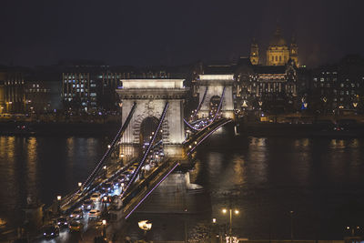 Illuminated chain bridge over river at night