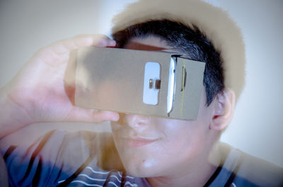 Boy looking in smart phone through cardboard virtual reality simulator
