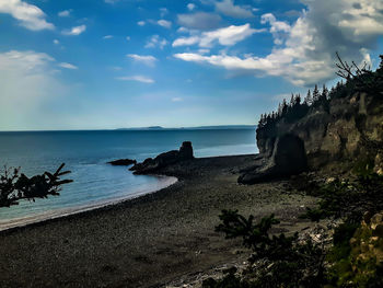 View of calm beach against cloudy sky
