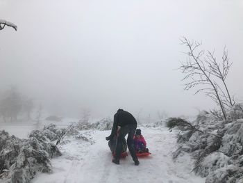 Rear view of people on snow covered landscape against sky