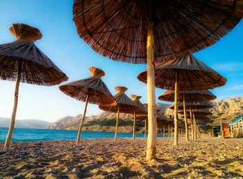 Traditional windmill on beach against clear blue sky