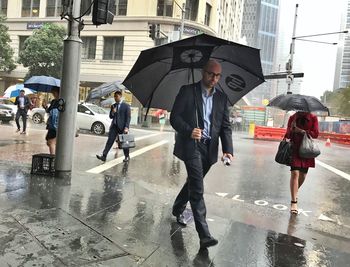 People walking on wet road during rainy season