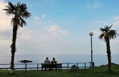 People relaxing at beach against sky