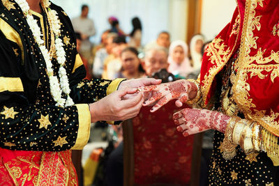 Asian muslim couple holding and putting ring each other hand in minangkabau wedding ceremony.