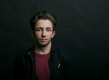 Portrait of confident young man standing against colored background