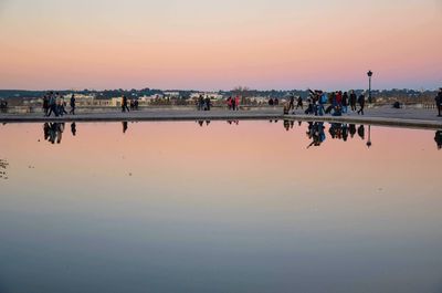 People on beach against clear sky during sunset