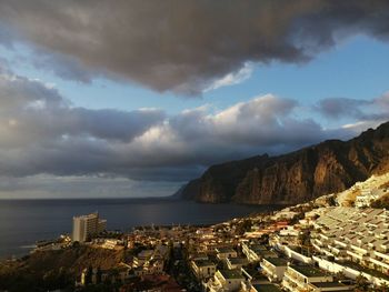 Aerial view of townscape by sea against sky