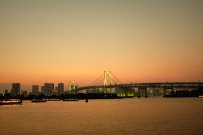 View of suspension bridge in city at sunset