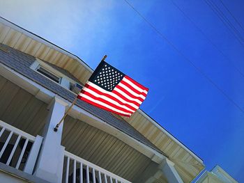 Low angle view of flags against buildings against blue sky