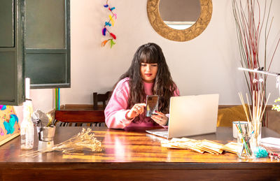 Portrait of young woman sitting on table at home