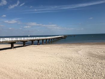 Pier on beach against sky