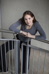 Portrait of smiling young woman standing against railing